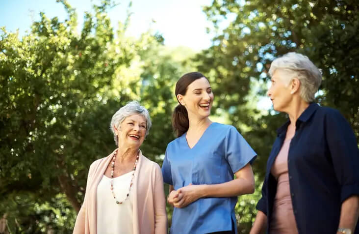Senior women going for a walk in the garden with a nurse in Spring Lake