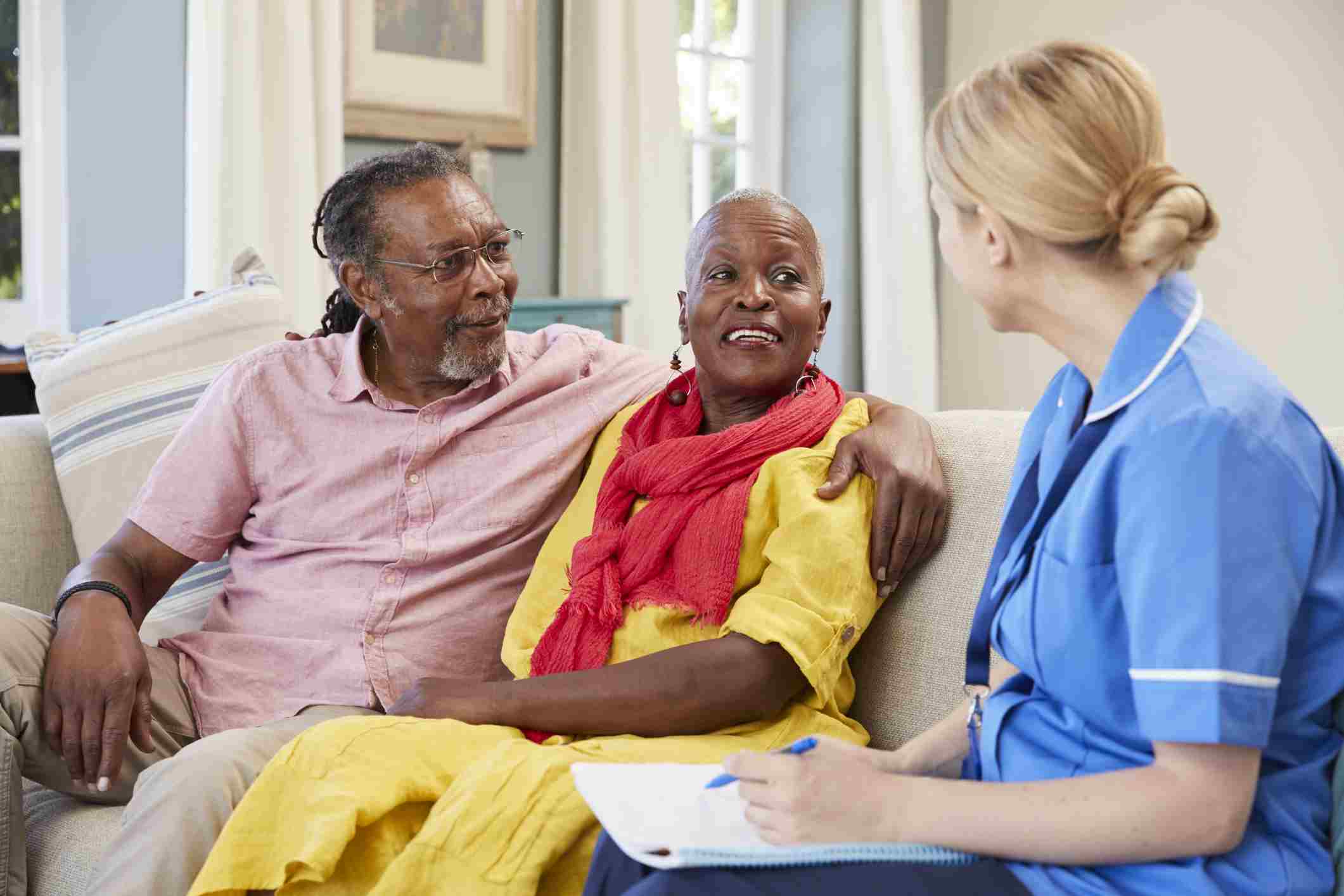 A nurse converses with an elderly couple seated on a couch, highlighting senior care in Spring Lake