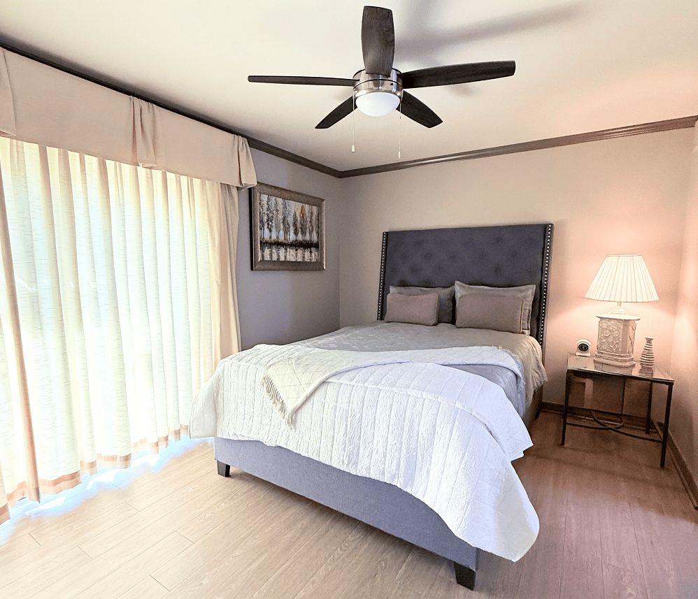 Assisted Living Apartment featuring a bed and a ceiling fan in a cozy bedroom in Spring Lake
