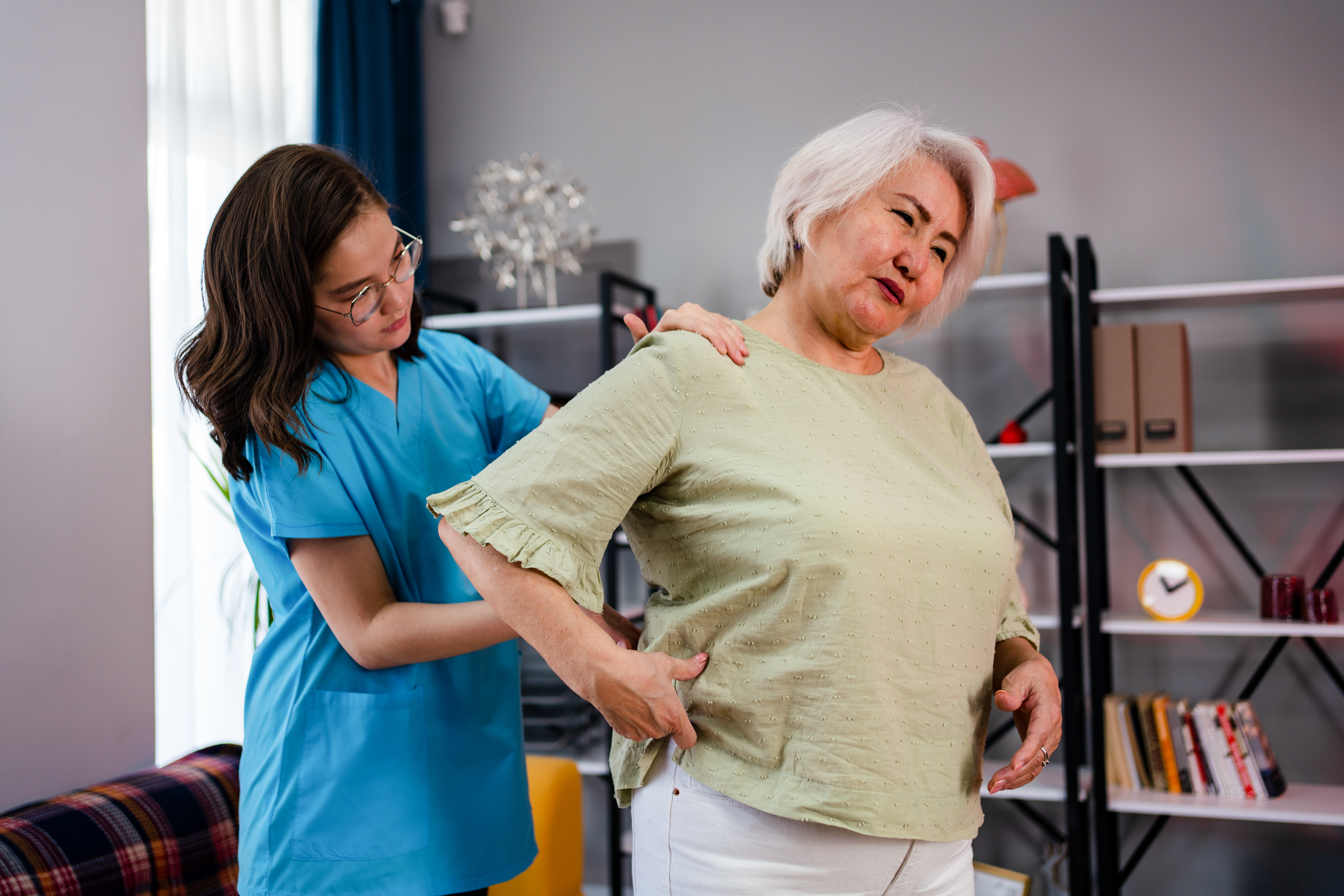 Senior adult woman Patient with Pain in the Backand and home healthcare nurse, physical therapist