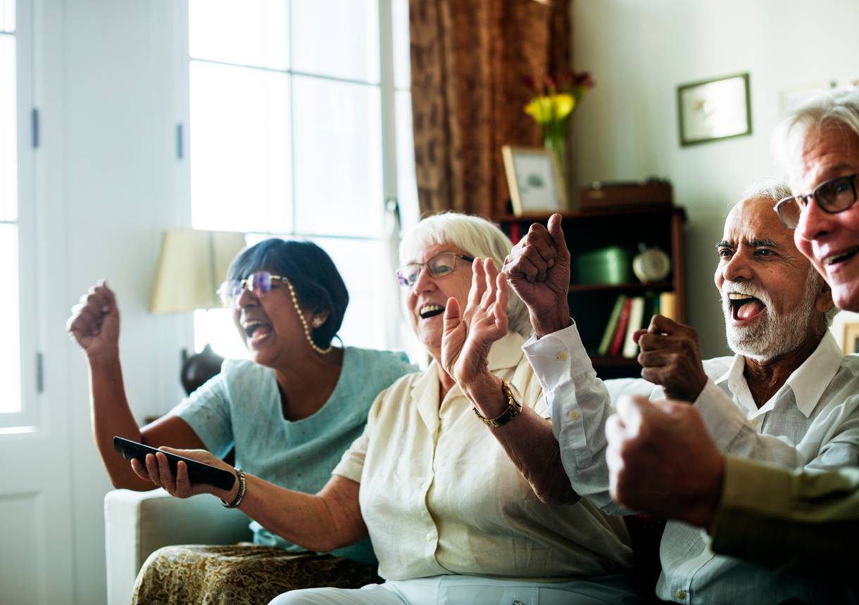 Seniors sitting together and cheering in a warm living room environment in Shreveport, LA