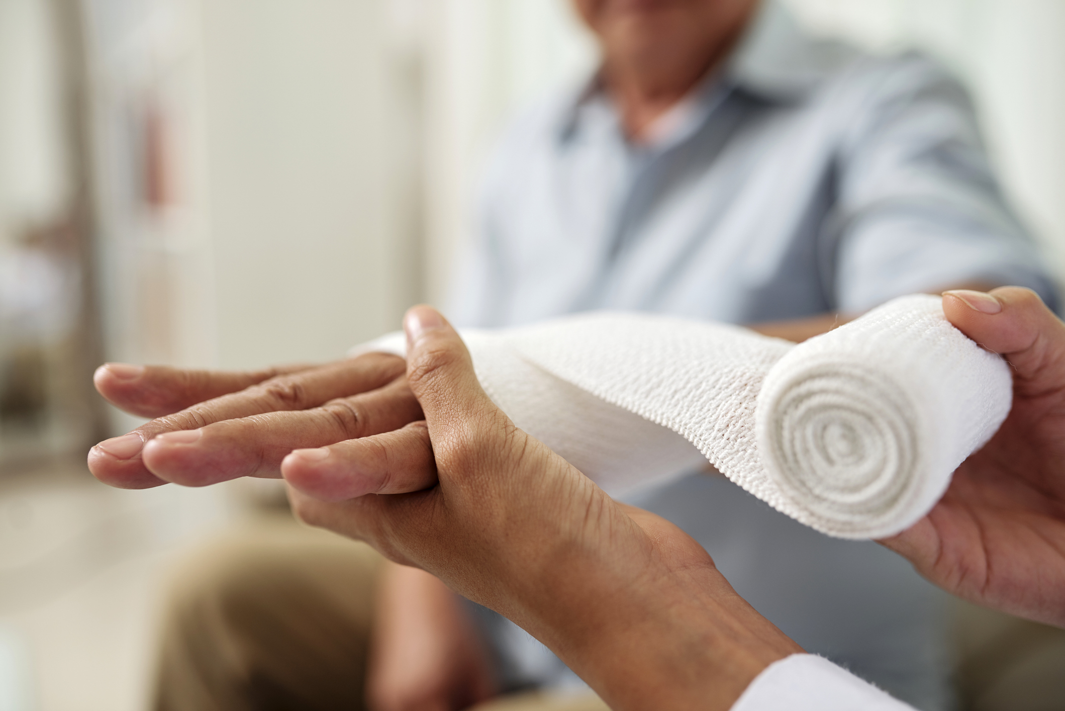 Doctor putting bandage on patient's hand