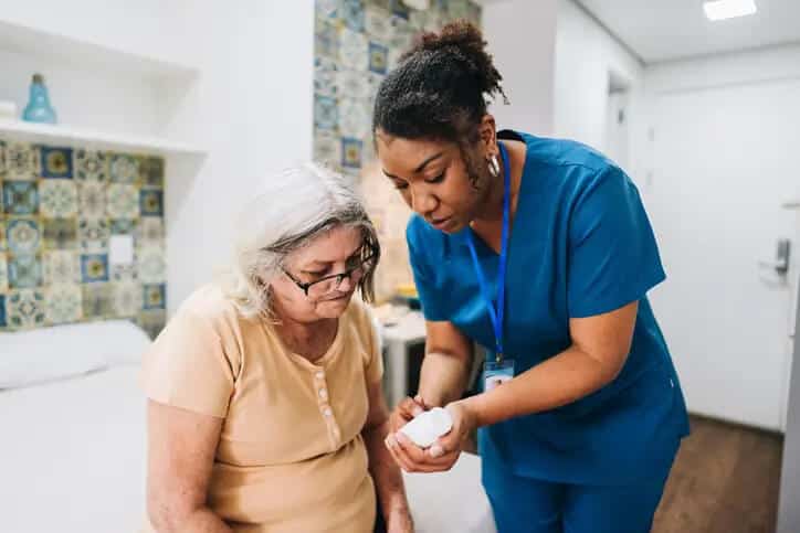 Caregiver assisting senior woman with her medications